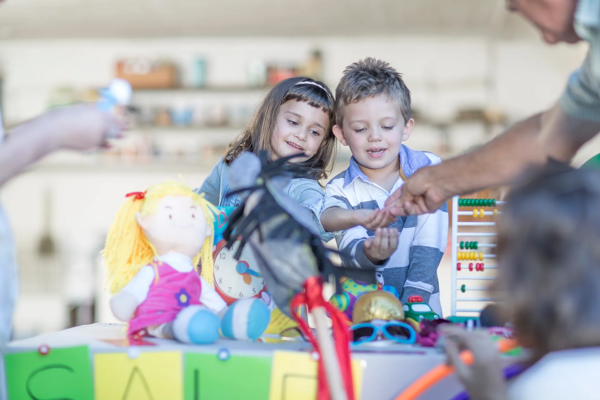 Dos nens munten una parada de joguines amb l'ajuda d'un adult