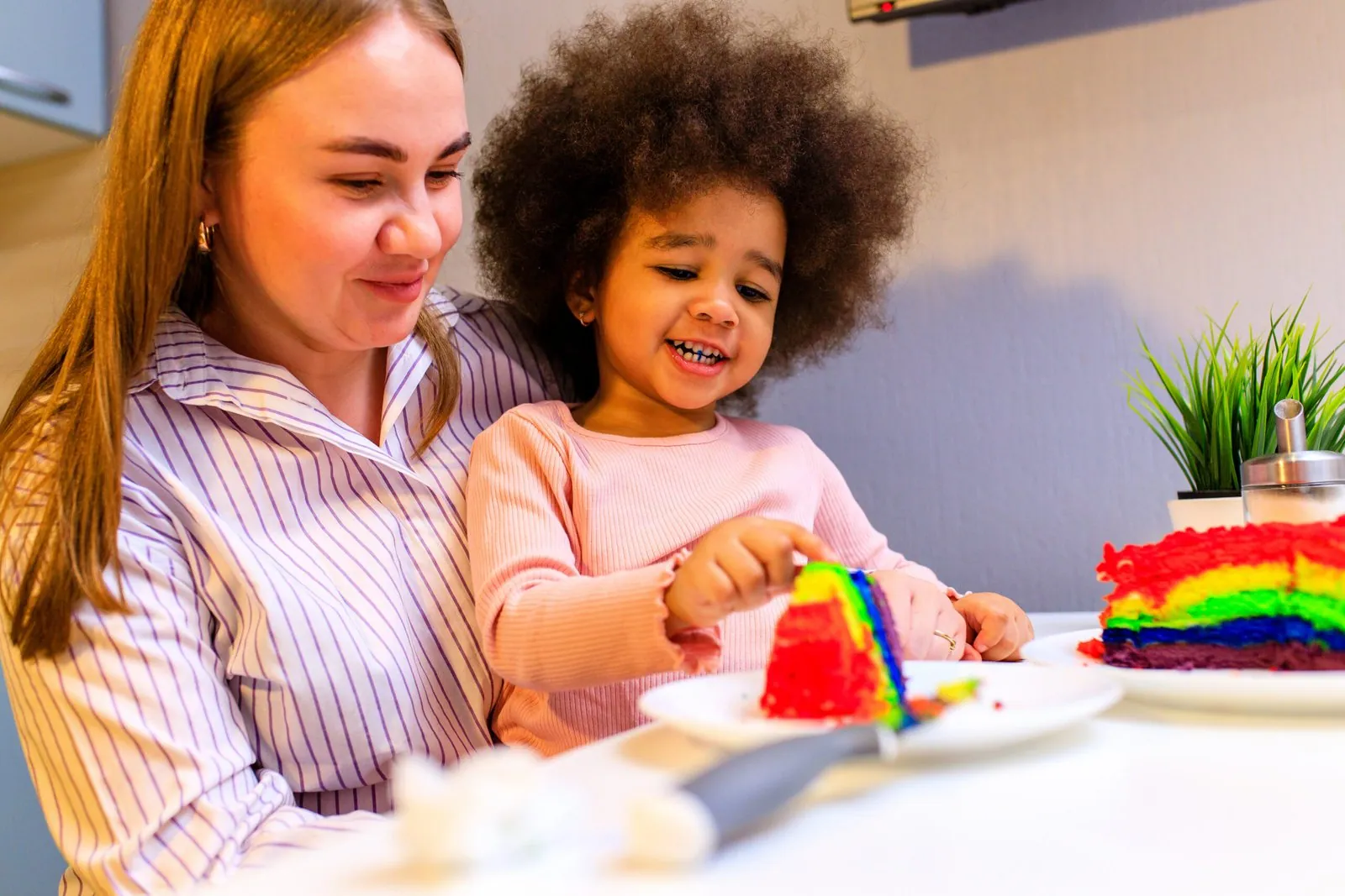 Una madre y su hija celebran con una tarta de colores en la cocina